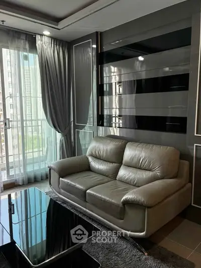 Modern living room with sleek leather sofa and floor-to-ceiling windows in a high-rise apartment.