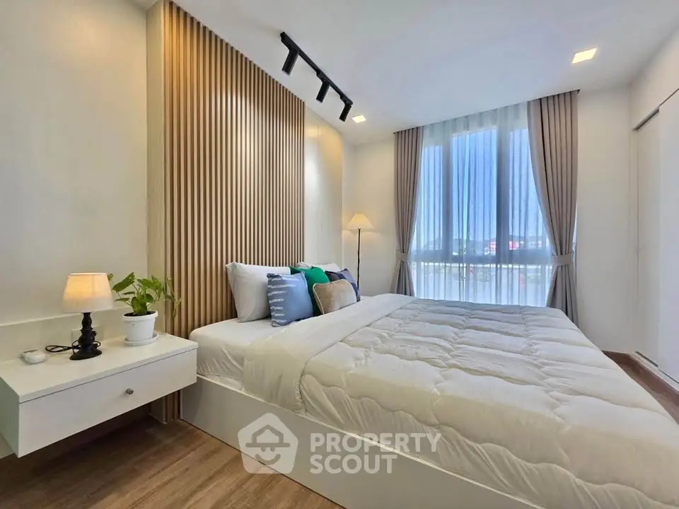 Modern bedroom with stylish decor and natural light, featuring a cozy bed and elegant wooden accents.