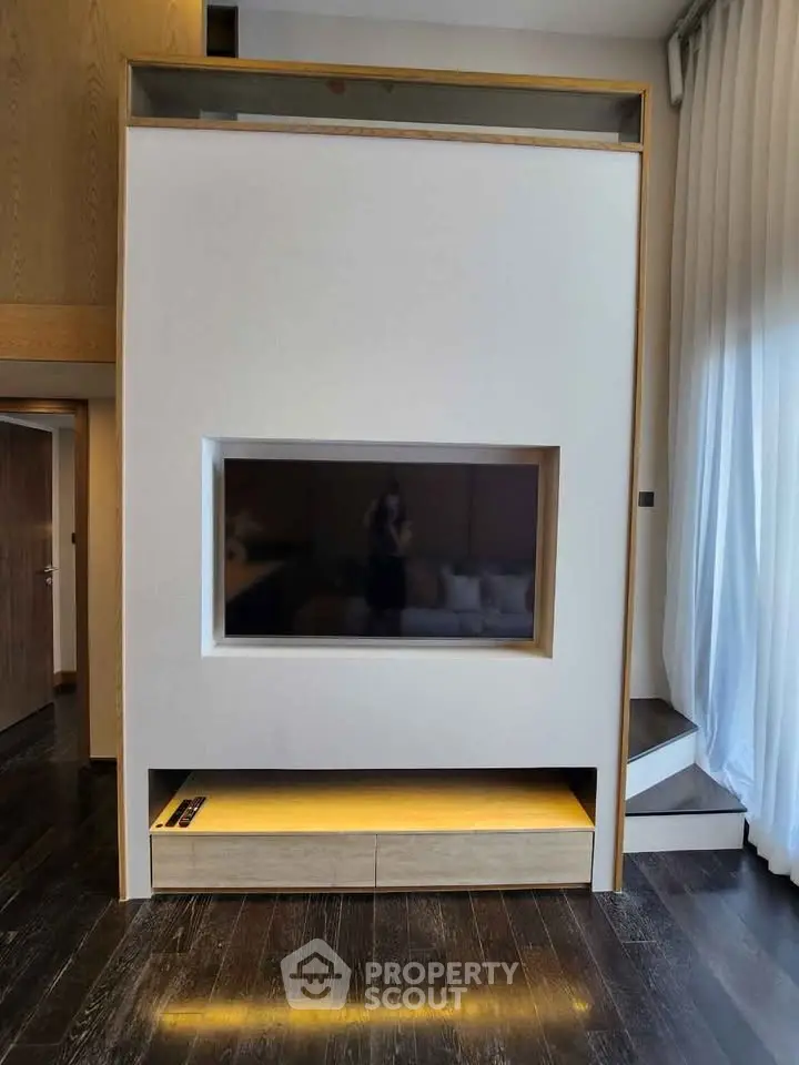 Modern living room with sleek built-in TV and elegant wooden flooring.