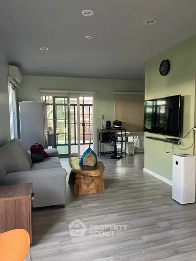 Spacious living room with modern decor and large windows leading to a balcony, perfect for relaxation.