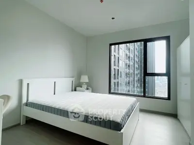 Modern minimalist bedroom with large window and city view in high-rise apartment.