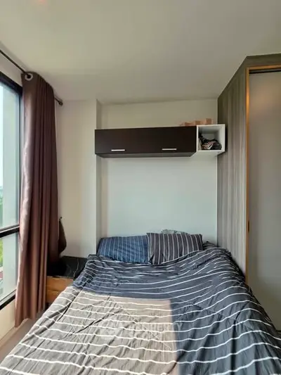 Cozy bedroom with striped bedding and modern wall-mounted storage in a bright apartment.