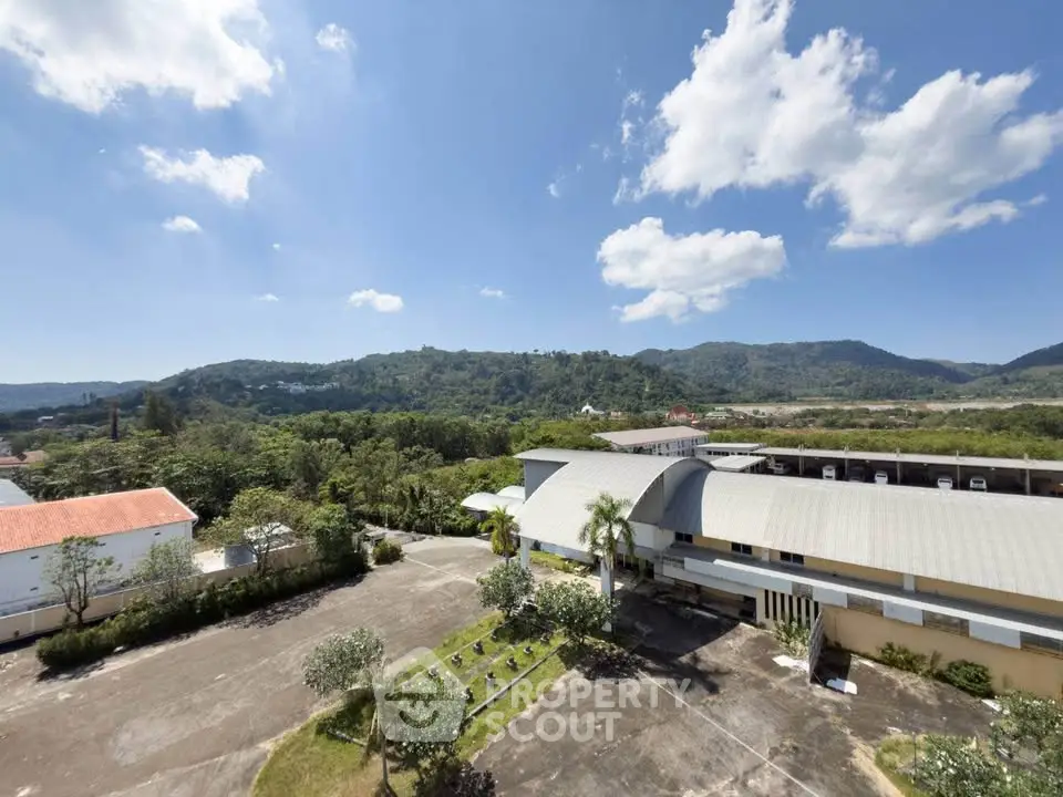 Stunning aerial view of a modern building surrounded by lush greenery and mountains under a clear blue sky.
