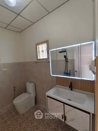 Modern bathroom with sleek fixtures and illuminated mirror, featuring a stylish sink and toilet.
