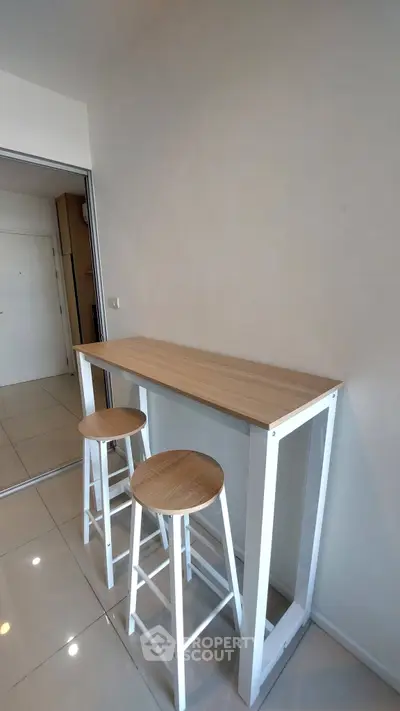 Modern minimalist kitchen with sleek bar table and stools, perfect for compact living spaces.
