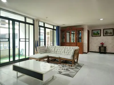 Spacious living room with large windows and modern furniture in a bright apartment.