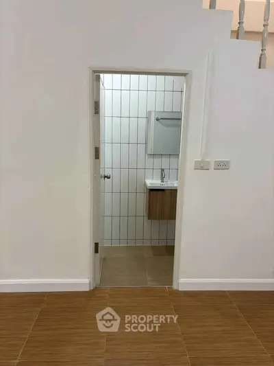 Modern minimalist bathroom entrance with sleek tiles and compact vanity unit.