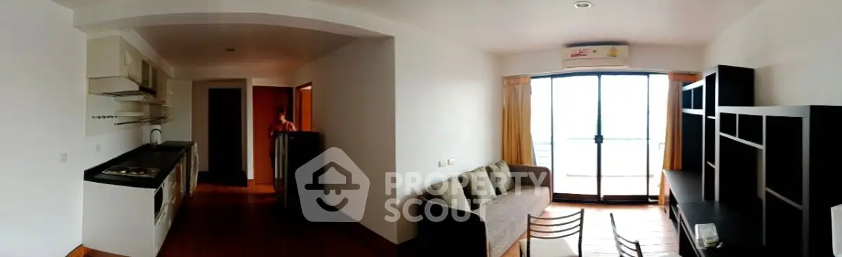 Spacious open-plan living room with modern kitchen and balcony access, perfect for urban living.