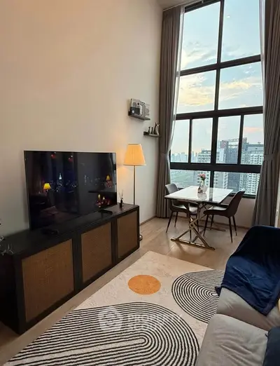 Stylish living room with large windows offering stunning city views, modern decor, and cozy ambiance.