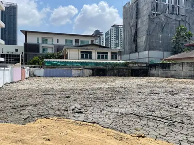 Vacant land plot in urban area with surrounding buildings, ideal for development.