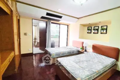 Spacious bedroom with twin beds and balcony access in modern apartment.