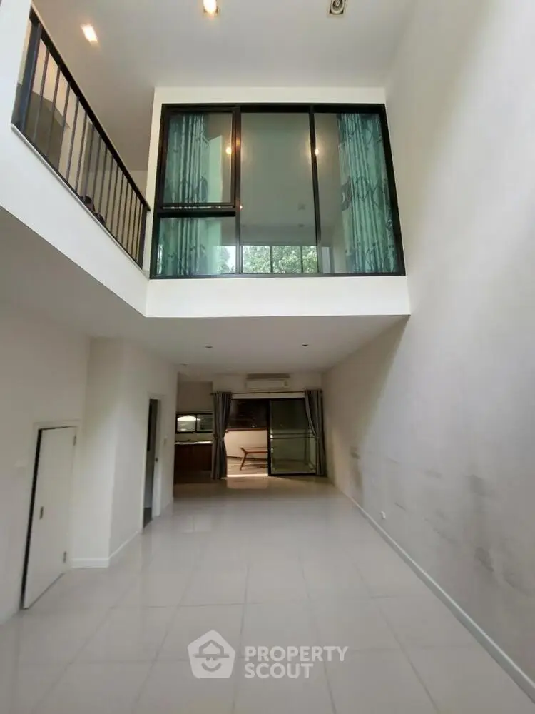 Spacious modern living room with high ceiling and large windows in a contemporary home.