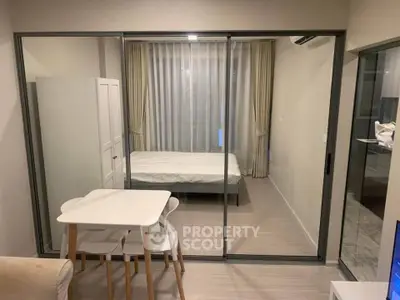 Modern studio apartment with glass partition, cozy dining area, and elegant bedroom setup.