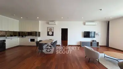 Spacious modern living room with open kitchen and stylish furniture, featuring hardwood floors and natural light.