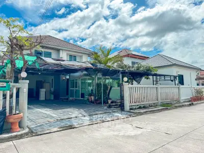 Charming suburban house with spacious driveway and lush greenery under a bright blue sky.