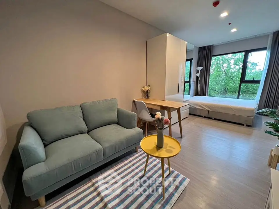 Modern studio apartment with cozy living area and large windows offering a serene view.