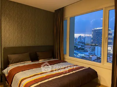 Modern bedroom with city view, featuring a cozy bed and large window overlooking the skyline.