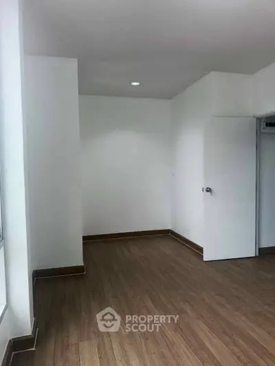Spacious empty room with wooden flooring and white walls, ideal for customization.