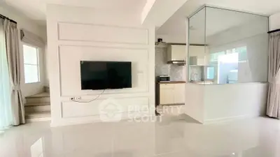 Modern open-plan living room with wall-mounted TV and sleek kitchen area