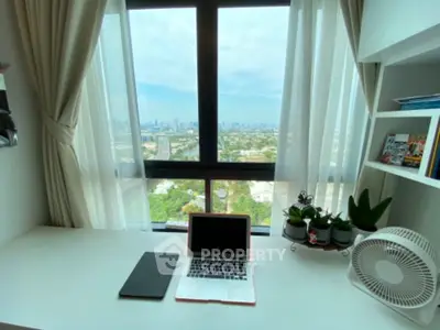 Bright study room with city view, featuring a desk, laptop, and plants by the window.