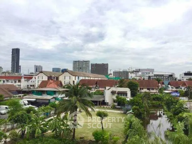 Scenic urban view with lush greenery and residential buildings under a cloudy sky.