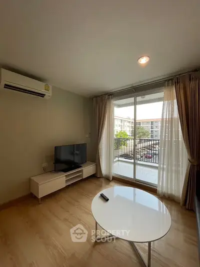 Modern living room with balcony view, featuring sleek furniture and natural light.