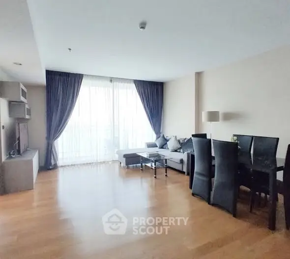 Spacious living room with elegant dining area and large windows.