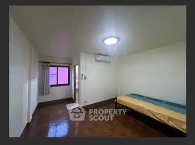 Spacious bedroom with single bed and air conditioning in minimalist style.