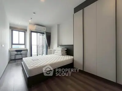 Modern bedroom with large window and balcony access in a stylish apartment.
