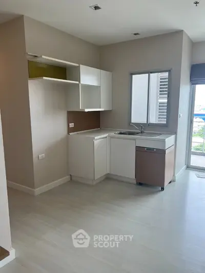 Modern minimalist kitchen with sleek cabinetry and large window offering natural light.