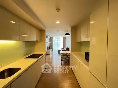 Modern open-layout kitchen leading to a spacious living room with natural light.