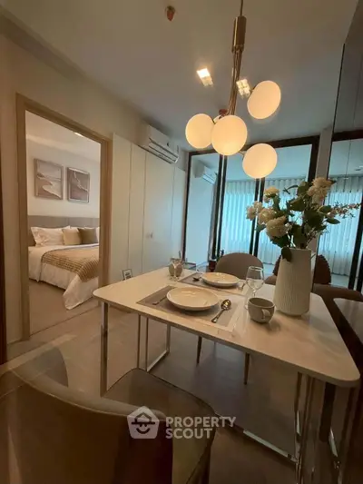 Modern dining area with elegant lighting and view into cozy bedroom