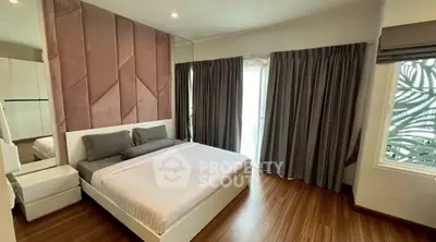 Modern bedroom with stylish decor and large window, featuring elegant curtains and wooden flooring.