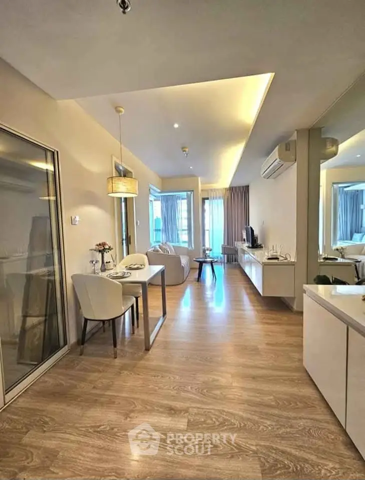 Modern living room with open layout and stylish decor, featuring wooden flooring and elegant lighting.