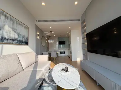 Modern living room with open kitchen, sleek furniture, and large TV setup