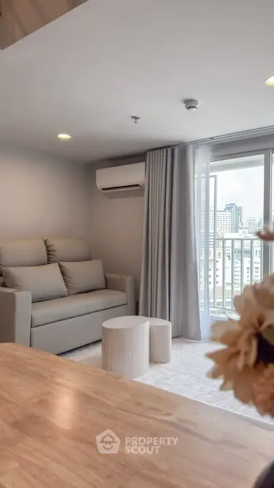 Modern living room with city view, featuring sleek furniture and large windows for natural light.
