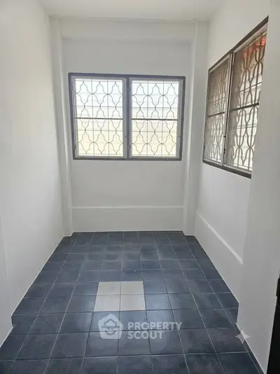 Spacious tiled room with large windows and natural light, perfect for versatile use.