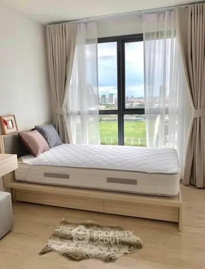 Bright bedroom with large window offering stunning city view, modern decor, and cozy ambiance.