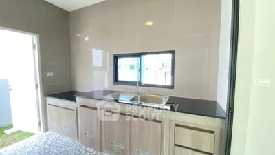 Modern kitchen with sleek cabinetry and stylish tile flooring, featuring a large window for natural light.