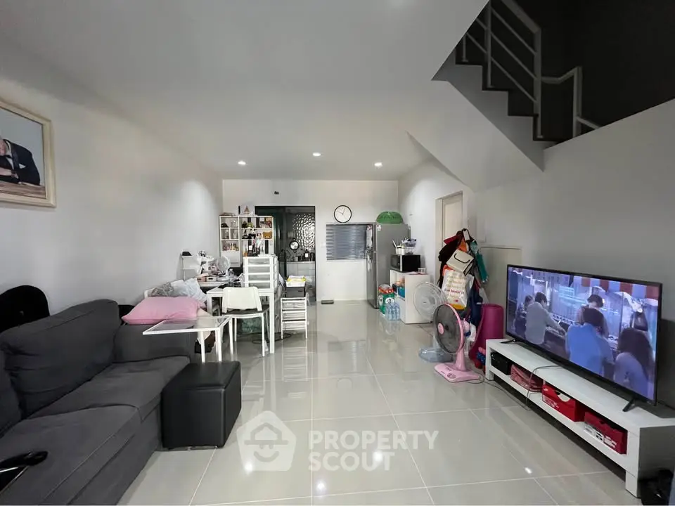 Spacious modern living room with sleek tile flooring and cozy seating area, perfect for family gatherings.