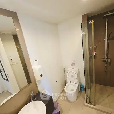 Modern bathroom with glass shower and sleek fixtures in contemporary apartment.