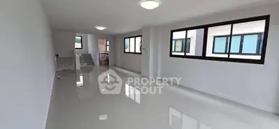 Spacious open-plan living area with large windows and glossy tiled floors, perfect for modern living.