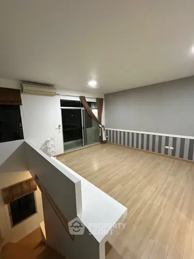 Spacious modern living room with wooden flooring and large windows for natural light.