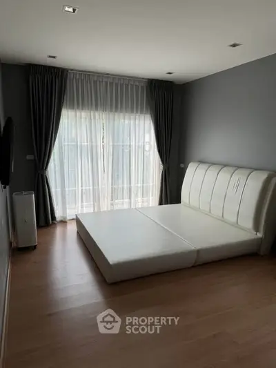 Spacious bedroom with modern minimalist design and large window for natural light.