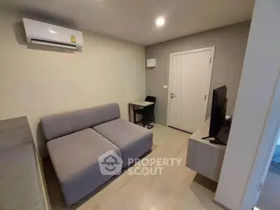 Modern living room with gray sofa, TV, and air conditioning in a cozy apartment.