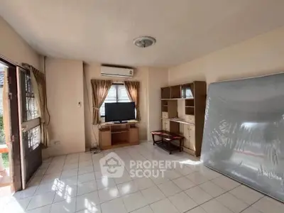 Spacious living room with tiled floor, TV, and natural light, perfect for relaxation.