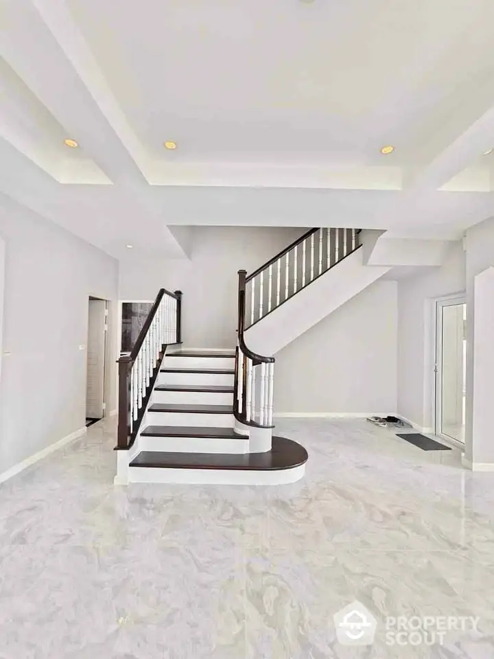 Elegant modern staircase in spacious living area with marble flooring and recessed lighting.