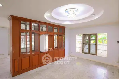 Spacious living room with elegant wooden cabinetry and modern ceiling light fixture.