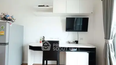 Modern study area with desk, TV, and fridge in a bright apartment