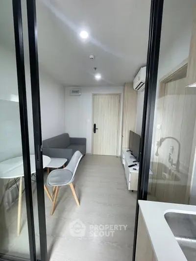 Modern living room with sleek furniture and glass partition in a stylish apartment.
